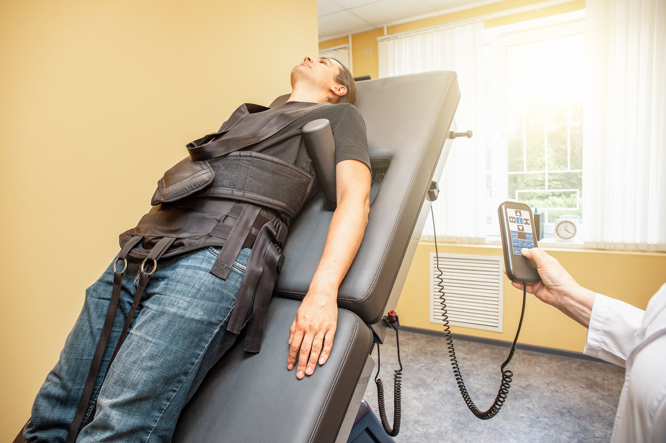 A patient in the harness on an inclined decompression table while the clinician operates the controls